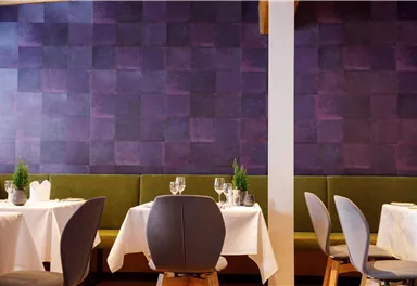 A stylish restaurant with elegant tables and modern chairs. The walls are designed in a beautiful shade of purple.