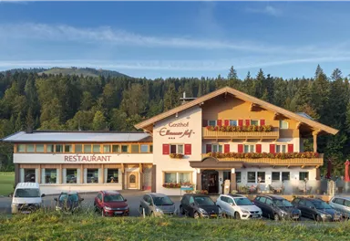 An inviting inn with a restaurant in a rural setting. The building is surrounded by trees and offers a beautiful view of the mountains.
