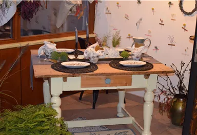 A beautifully decorated table with plates and natural materials. In the background, flowers and plant patterns can be seen on the wall.