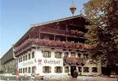 Ein traditionelles Gasthaus mit Balkonen voller Blumen. Das Gebäude hat eine rustikale Architektur und befindet sich in einer ruhigen Umgebung.