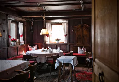 Ein gemütlicher Raum mit Holzwänden und einem Tisch in der Mitte. Sanftes Licht fällt durch die Fenster und schafft eine einladende Atmosphäre.