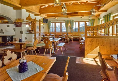 Ein gemütliches Restaurant mit Holzdekor und mehreren Tischen. Große Fenster sorgen für viel Tageslicht und eine einladende Atmosphäre.
