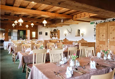 A cozy restaurant with wooden decor and tables set for guests. The atmosphere is inviting and friendly.
