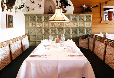 A cozy dining area with a festively set table and decorative walls. The environment is rustic with a warm atmosphere.