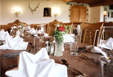 An elegantly set table in a cozy restaurant. The table decoration consists of napkins, glasses, and a bouquet of flowers.