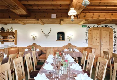 A cozy restaurant with wooden furniture and an inviting atmosphere. The table is festively set and the walls are decorated with antique elements.