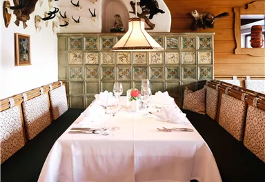 A cozy dining area with a festively set table and decorative walls. The environment is rustic with a warm atmosphere.