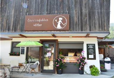 An inviting store with the sign "Nutrition Culture keISer". There are plants and furniture in the outdoor area, including a sunshade.