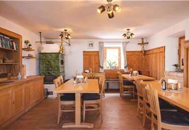 Ein gemütlicher Raum mit Holztischen und Stühlen. Die Wände sind aus Holz, und das Licht ist warm und einladend.
