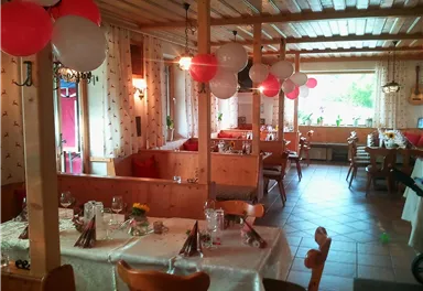 A cozy restaurant with festively decorated tables. Red, white, and black balloons adorn the room.