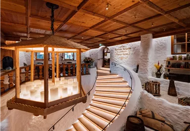 Ein eleganter Innenraum mit einer geschwungenen Treppe und warmem Licht. Holzdetails und gemütliche Dekoration schaffen eine einladende Atmosphäre.