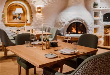 Ein gemütliches Restaurant mit einem Holzofen und stilvollen Möbeln. Der Tisch ist elegant gedeckt und schafft eine einladende Atmosphäre.