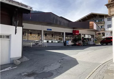 A modern shop in a picturesque setting. The street gently slopes and shopping carts can be seen in front of the entrance.