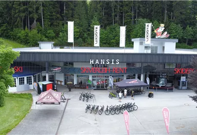 Ein Geschäft für Sportartikel mit Fahrradverleih und Ski-Ausrüstung. Draußen stehen mehrere Fahrräder und Zelte.
