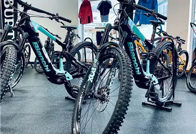 Ein Fahrradgeschäft mit mehreren Mountainbikes der Marke Bianchi. Die Fahrräder haben auffällige Farben und stehen auf einem schwarzen Boden.