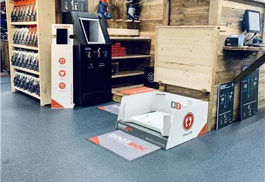 Ein moderner Skiverleih mit Holzregalen und Skiausrüstung. Im Vordergrund steht ein Schuh-Scanner für die Kunden.