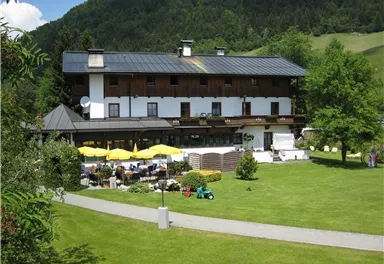 Ein gemütliches Hotel mit einem großen Garten und Terrassen. Umbaut von Bäumen und Wiesen, ideal für Entspannung im Freien.
