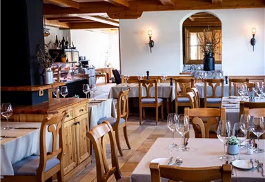 An elegant restaurant with wooden furniture and set tables. The atmosphere is welcoming and cozy.