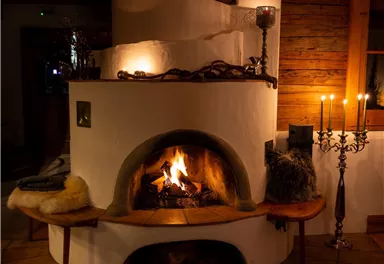A cozy stone fireplace with a blazing fire. The surroundings are warmly lit and radiate an inviting atmosphere.
