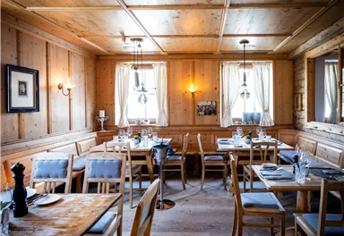 A cozy restaurant with wooden walls and a wooden ceiling. The tables are simply set and flooded with daylight.