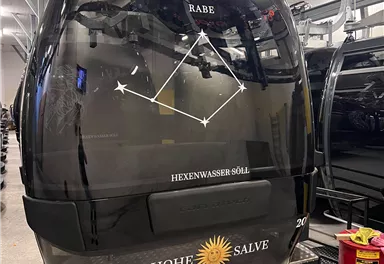 A black gondola with a print of a star constellation. In the background, more gondolas are visible.