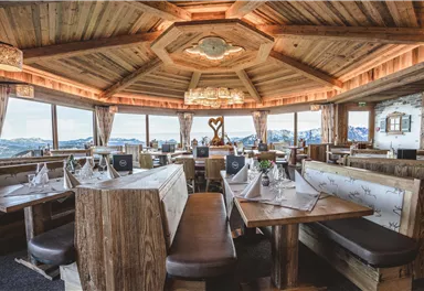 Ein gemütliches Restaurant mit Holzinterieur und großen Fenstern. Die Aussicht auf die Berge ist atemberaubend.