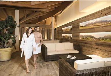 Ein modernes Spa mit holzverkleideten Wänden und gemütlichen Sitzbereichen. Ein Paar in Bademänteln genießt die entspannende Atmosphäre.