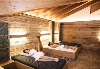 Ein entspannender Wellnessbereich mit zwei Liegen. Die Atmosphäre ist ruhig und gemütlich, ideal für Erholung.