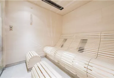 Ein modernes Dampfbad mit hellen, holzfarbenen Bänken. Die Wände sind klar und minimalistisch gestaltet.