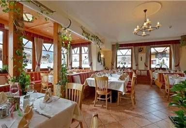 A cozy restaurant with wooden furniture and well-set tables.  
Large windows provide plenty of natural light and a view of the surroundings.