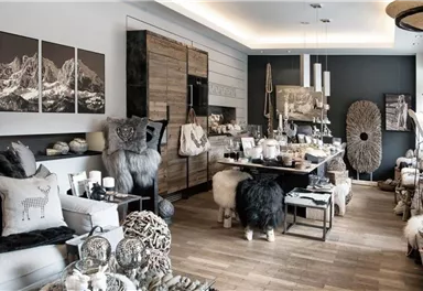 Ein stilvolles Wohnzimmer mit modernen Möbeln und gemütlichen Dekorationen. Die farbliche Gestaltung ist neutral und elegant, mit einigen Kunstwerken an den Wänden.