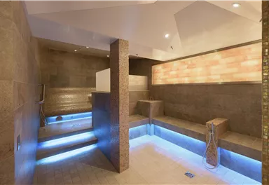 Ein modernes Spa mit sanften Beleuchtungseffekten. Die Wände sind aus Stein und es gibt bequeme Sitzgelegenheiten zum Entspannen.