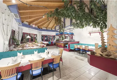 Ein gemütliches Restaurant mit Holzdecke und farbigen Sitzplätzen. Die Tische sind festlich gedeckt und bieten Platz für viele Gäste.
