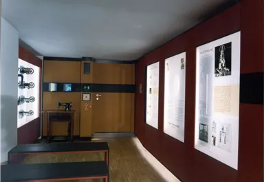 An exhibition space with walls decorated with informational posters and pictures. In the center, there are two long benches.
