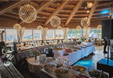 An elegant interior with a wooden ceiling and modern lamps. A buffet table is laid out with a variety of dishes.