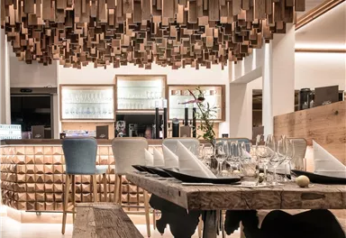 A modern restaurant with a stylish wooden decor. The ceiling light and the wooden paneling create a warm atmosphere.