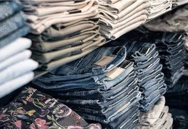 A large selection of folded jeans in various colors and patterns. The pants are neatly stacked and well organized.