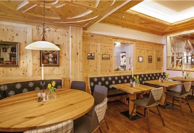 A cozy restaurant with wood paneling and round tables. The decor is rustic and inviting, perfect for a relaxed meal.