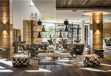 Ein stilvolles und modernes Wohnzimmer mit Holzdekor und gemütlichen Möbeln. Große Fenster lassen viel Licht herein und schaffen eine einladende Atmosphäre.