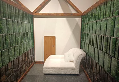 Ein stylischer Raum mit einem weißen Sofa und Wänden, die mit Bildern von Pflanzen dekoriert sind. Die Atmosphäre wirkt ruhig und einladend.