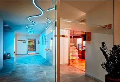 Ein moderner Innenraum mit sanften, geschwungenen Lichtern. Die Kombination aus hellem Boden und stylischen Elementen schafft eine einladende Atmosphäre.