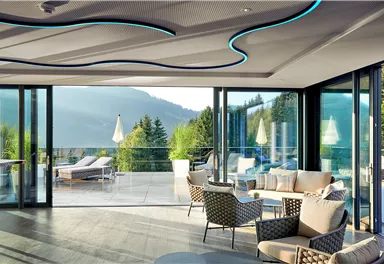 Ein eleganter Wohnraum mit großen Fenstern, die einen Blick auf die Berge bieten. Die Einrichtung ist modern und einladend.