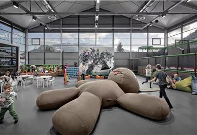 Ein moderner Spielraum mit vielen Kindern, die aktiv spielen. In der Mitte liegt ein großes, weiches Stofftier.