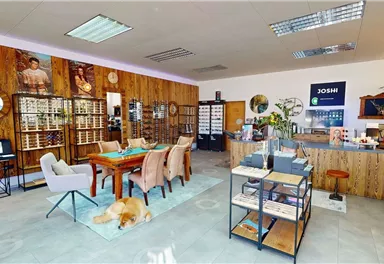 Ein modern gestalteter Geschäftsraum mit Holzwänden und eleganten Möbeln. Es gibt einen Tisch, Stühle und eine freundliche Atmosphäre.