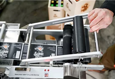 Eine Produktionsmaschine mit einer Person, die gerade eine Rolle anpasst. Im Hintergrund sind Kisten mit Produkten sichtbar.