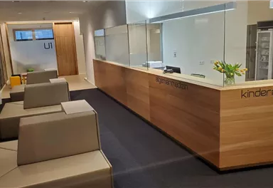 A modern reception area with a wooden counter and seating. The room is bright and friendly designed, ideal for a pediatric practice.