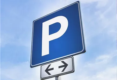 A blue parking sign with a large "P" on it. Below, an arrow symbol indicates the direction to the parking facilities.