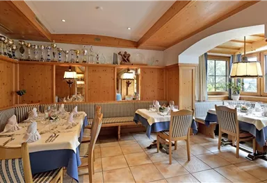 Ein gemütliches Restaurant mit holzverkleideten Wänden und eleganten Tischdecken. Die Atmosphäre ist einladend und freundlich, ideal für ein Essen mit Familie oder Freunden.