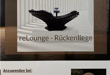 Eine elegante Rückenliege steht in einem modernen Raum mit vertikalen Linien. Die Liege ist mit einem Display ausgestattet und bietet Entspannung für gestresste Menschen.