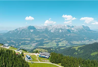 Eine beeindruckende Berglandschaft mit grünen Wiesen und Hügeln. Der klare Himmel und die Wolken sorgen für eine malerische Aussicht.